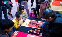 Warga Kota Hanoi membawa anak ke tempat meminta aksara awal tahun di Danau Van