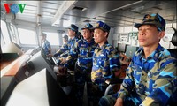 Vietnamese marine police and patrol forces stand side by fishermen 